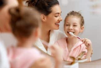 Niño cepillándose los dientes con supervisión de un adulto