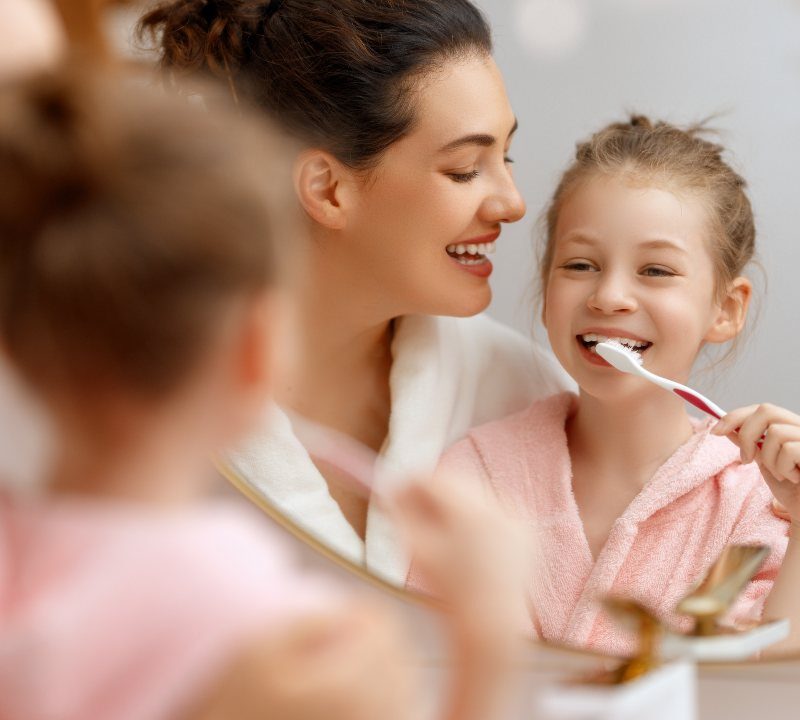 Niño cepillándose los dientes con supervisión de un adulto