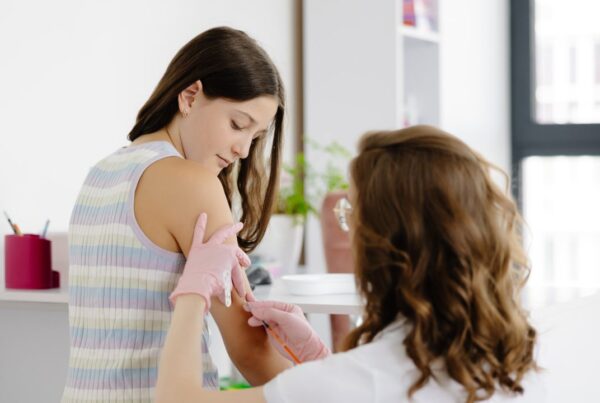 Un profesional de la salud preparando una dosis de la vacuna contra el VPH para un adolescente, destacando la prevención del cáncer desde edades tempranas.