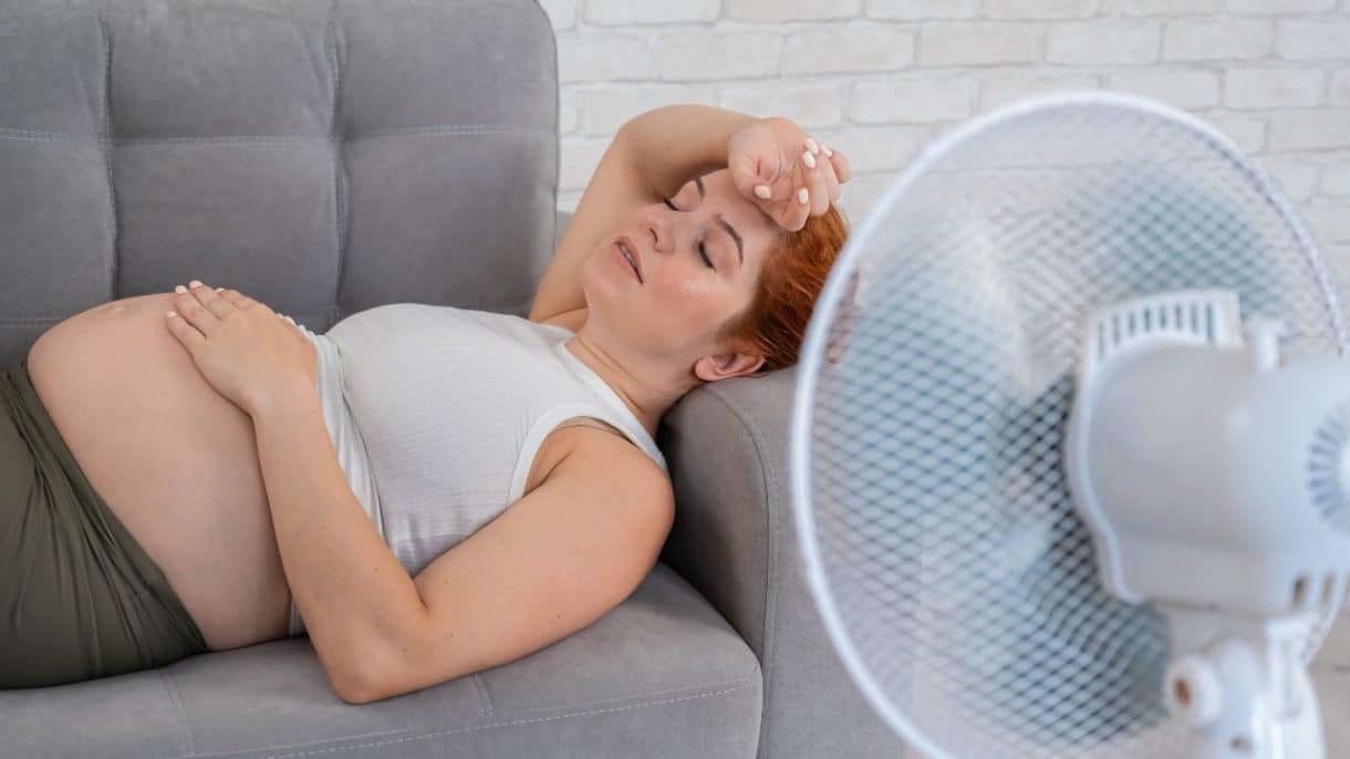 Mujer embarazada frente a ventilador en un ambiente caluroso para evitar efectos del calor