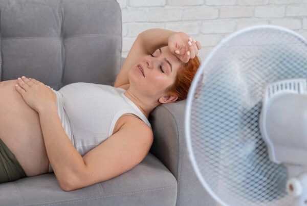Mujer embarazada frente a ventilador en un ambiente caluroso para evitar efectos del calor