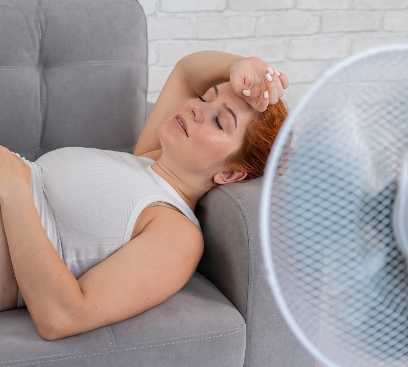 Mujer embarazada frente a ventilador en un ambiente caluroso para evitar efectos del calor