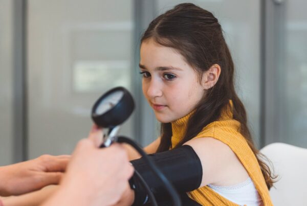 Médico midiendo la presión arterial a un niño en consulta pediátrica
