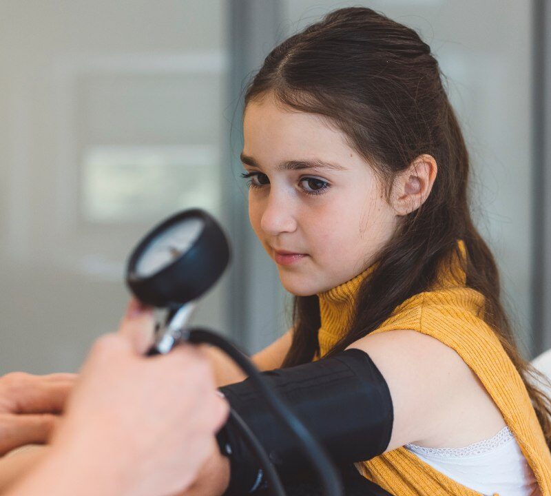 Médico midiendo la presión arterial a un niño en consulta pediátrica