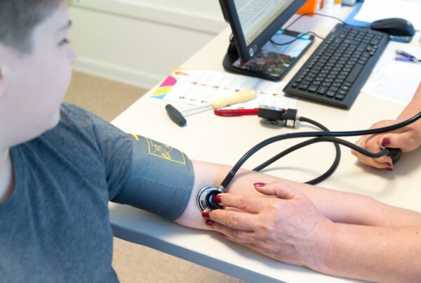 Un pediatra midiendo la presión arterial a un adolescente en una consulta médica, alertando sobre el aumento de la hipertensión pediátrica.