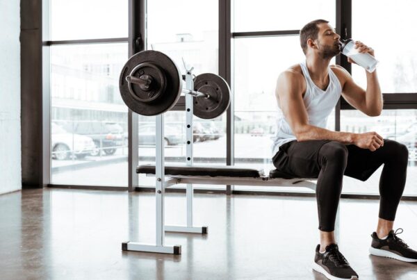 Batido de proteínas junto a una persona entrenando en el gimnasio
