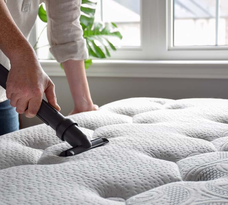Persona aspirando colchón para que esté limpio y libre de ácaros