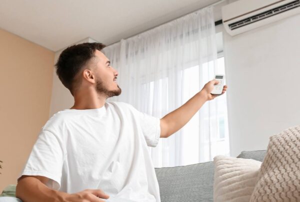 Persona ajustando aire acondicionado en casa con ambiente confortable