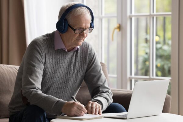Persona adulta estudiando idiomas con cuaderno y aplicación móvil