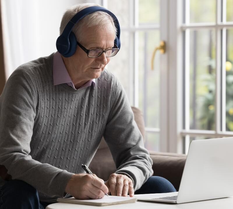 Persona adulta estudiando idiomas con cuaderno y aplicación móvil