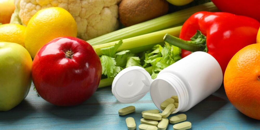 Pastillas y suplementos alimenticios junto a alimentos saludables