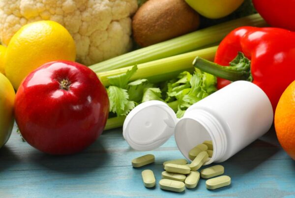 Pastillas y suplementos alimenticios junto a alimentos saludables