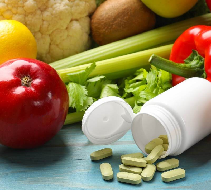 Pastillas y suplementos alimenticios junto a alimentos saludables
