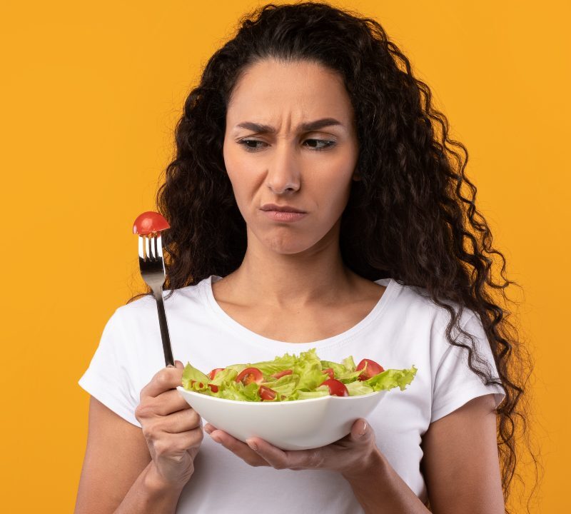 Persona cansada mirando plato pequeño durante dieta