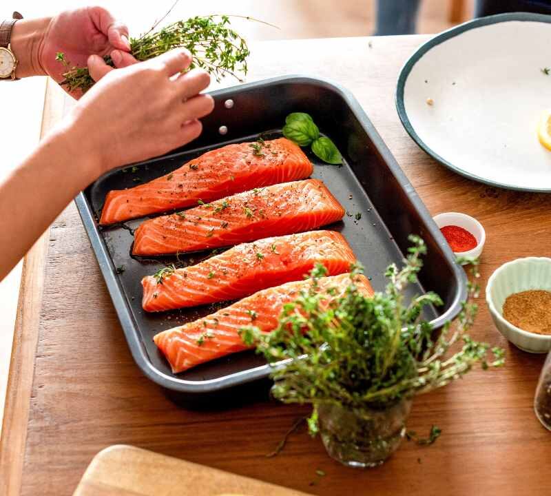 Persona cocinando con hierbas frescas y especias como alternativa a la sal