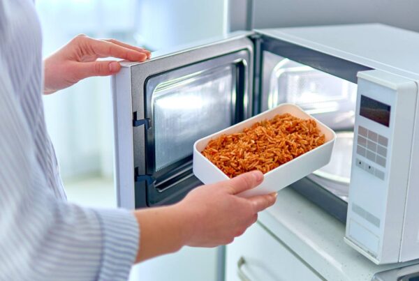 Persona utilizando microondas para calentar alimentos de forma segura
