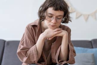 Adolescente con expresión triste mirando hacia abajo, representando el impacto emocional de las autolesiones