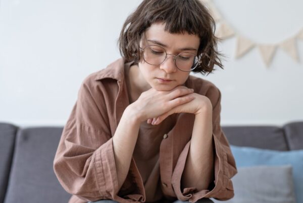 Adolescente con expresión triste mirando hacia abajo, representando el impacto emocional de las autolesiones