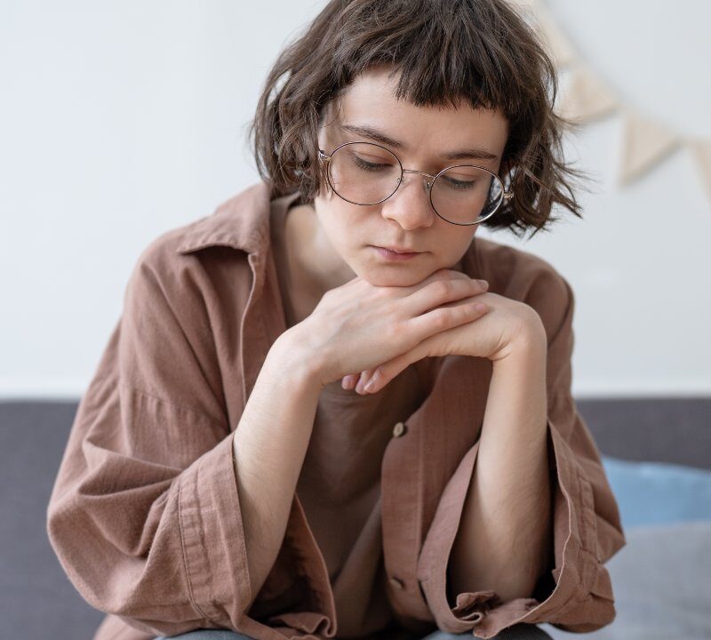Adolescente con expresión triste mirando hacia abajo, representando el impacto emocional de las autolesiones