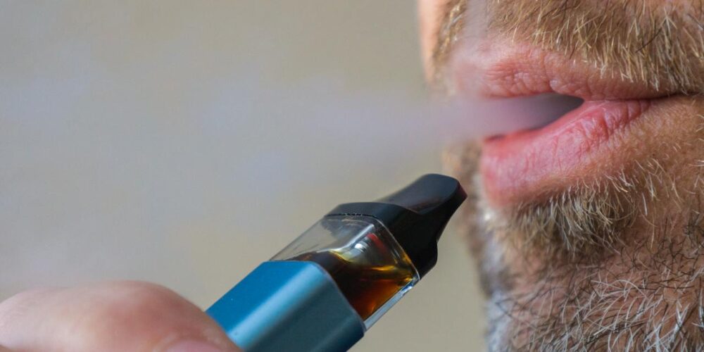 Persona vapeando cigarrillo electrónico con humo visible