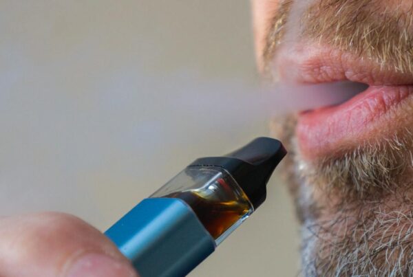 Persona vapeando cigarrillo electrónico con humo visible