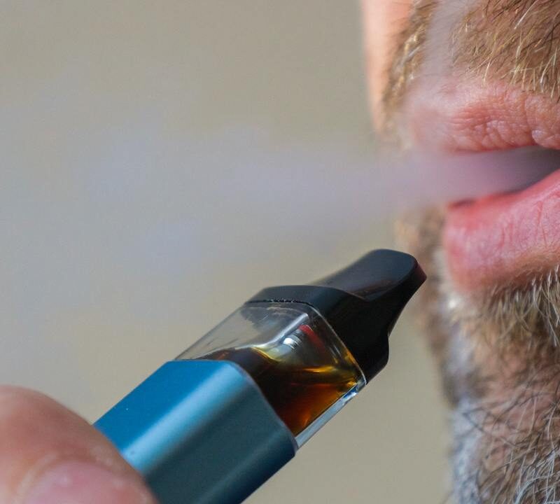 Persona vapeando cigarrillo electrónico con humo visible