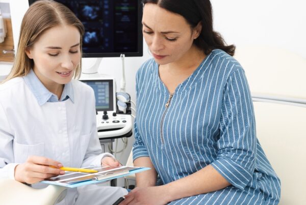 Mujer durante consulta ginecológica conversando con su médico sobre síntomas relacionados con la salud ovárica