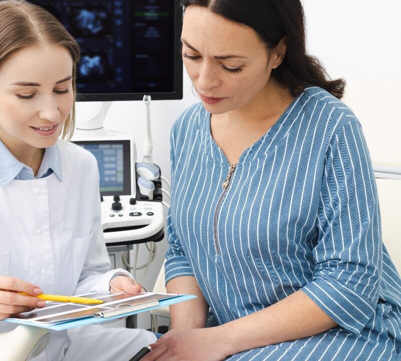 Mujer durante consulta ginecológica conversando con su médico sobre síntomas relacionados con la salud ovárica