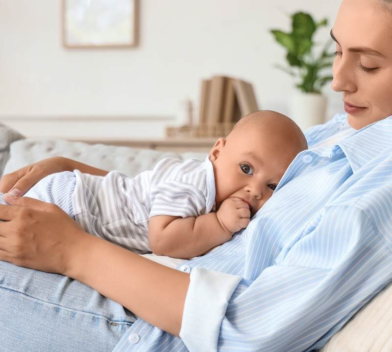 Madre en posparto descansando con su bebé en un entorno tranquilo