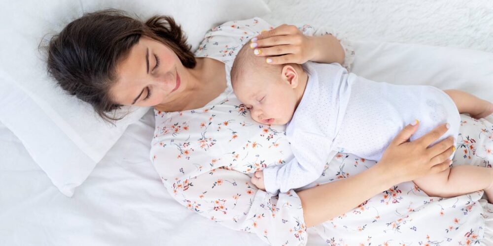 madre en cuidado posparto descansando con su bebé en casa