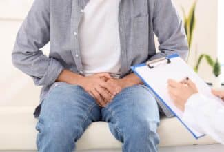 Hombre joven con dolor e inflamación en la zona testicular durante una consulta médica urológica