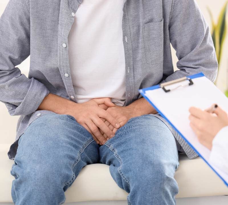 Hombre joven con dolor e inflamación en la zona testicular durante una consulta médica urológica