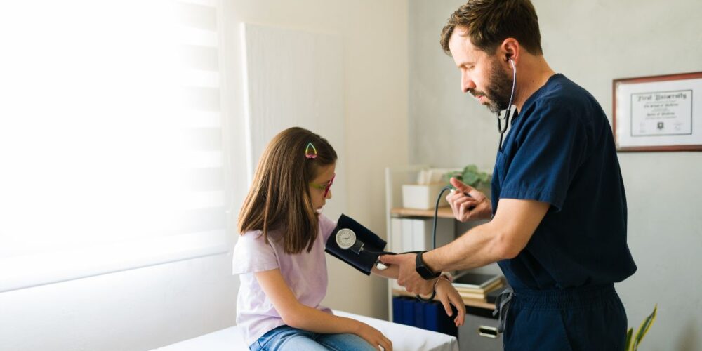 Niño en consulta médica midiendo presión arterial con tensiómetro