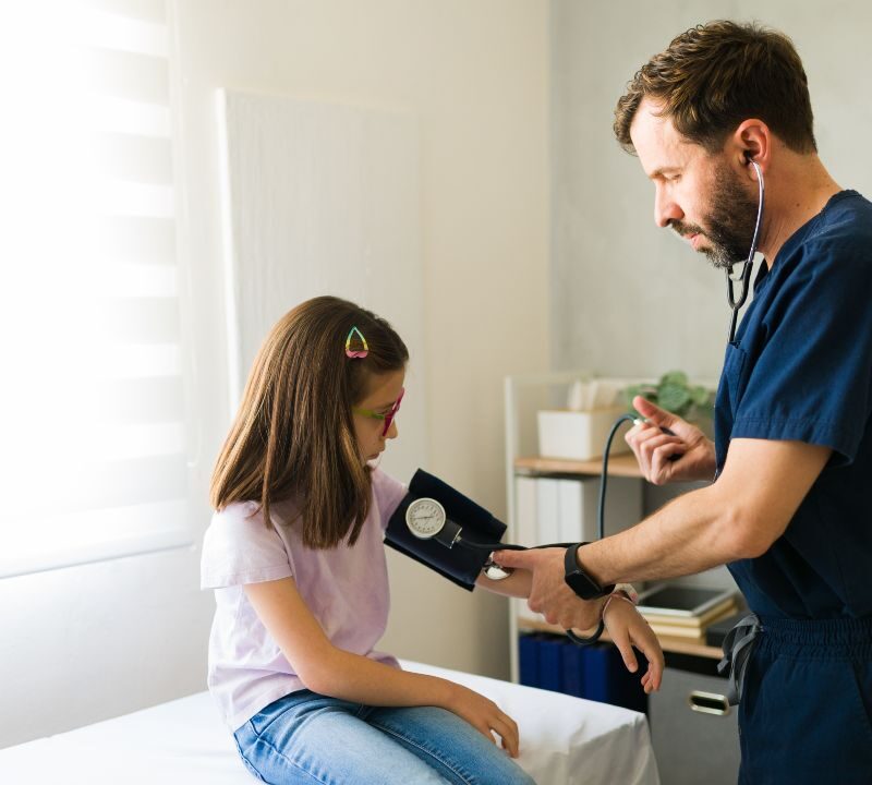 Niño en consulta médica midiendo presión arterial con tensiómetro