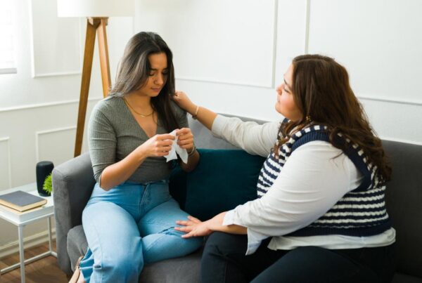 Mujer acompañando en silencio a una amiga triste mientras conversan en un sofá.